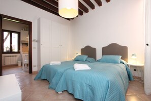 A bedroom with two beds, a white wardrobe, a bedside table with a lamp, and a window. - Puccini Historical Center (Venice)