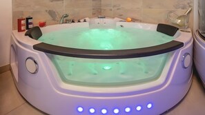 Ein Whirlpool mit Glasabdeckung, integrierten DĂŒsen und LED-Beleuchtung.