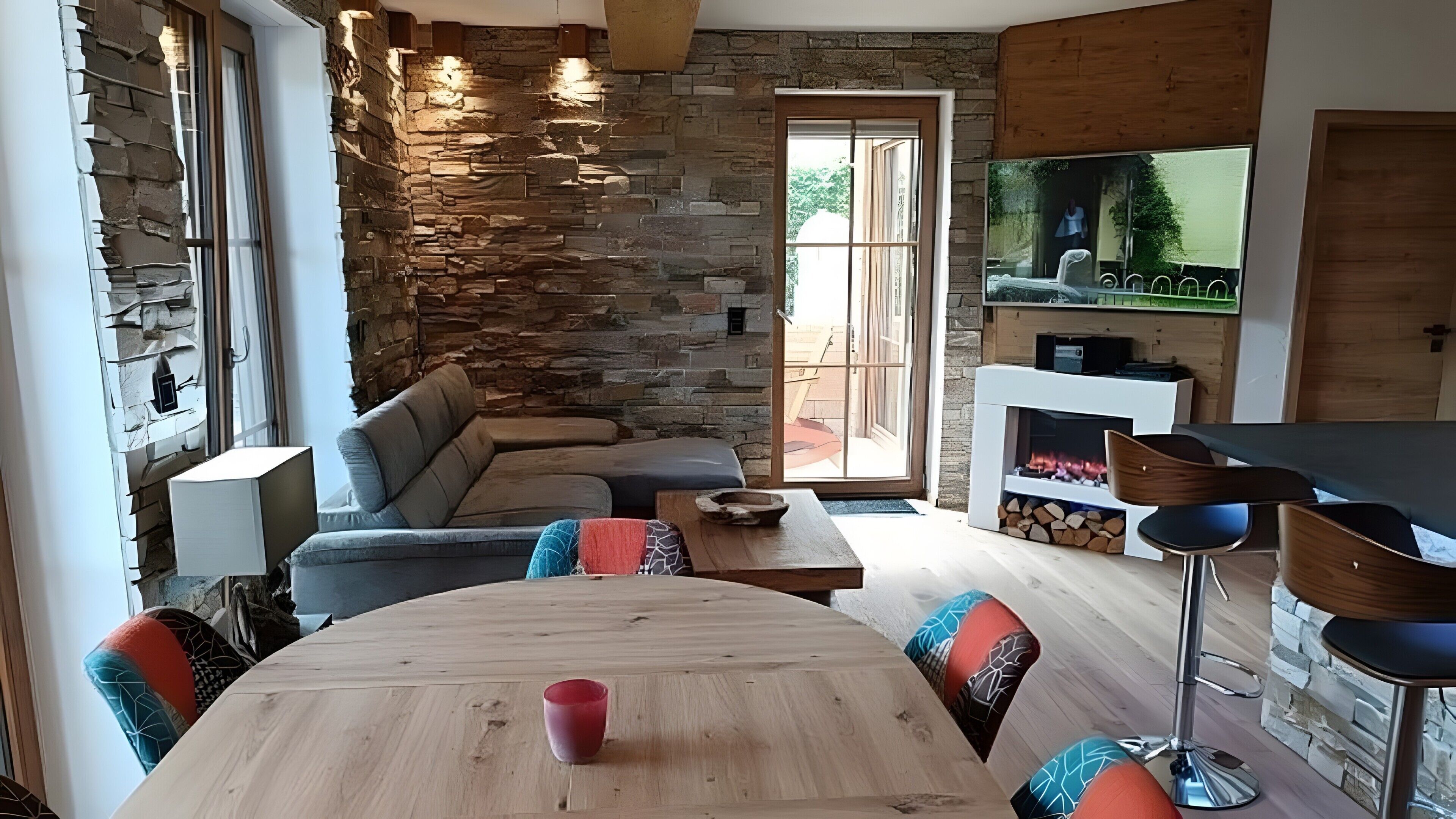 A modern living room with a stone wall, a sofa, a dining table, and a fireplace.