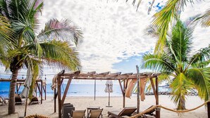 A beach with a wooden pergola, lounge chairs, and a rope barrier. - Family Paradise Views, Jacuzzi and Beach Club (Cruz de Huanacaxtle)