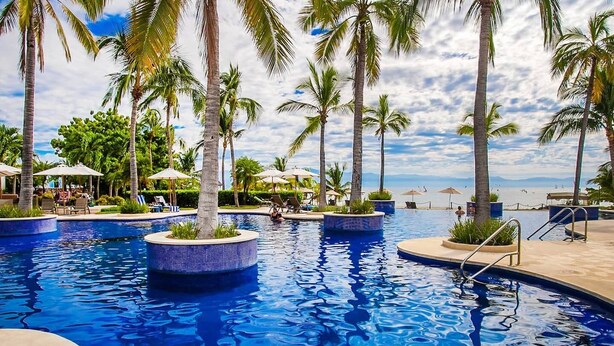 A swimming pool with palm trees, lounge chairs, and umbrellas. - Family Paradise Views, Jacuzzi and Beach Club (Cruz de Huanacaxtle)