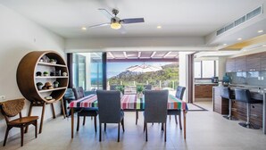 A modern dining area with a table, chairs, a ceiling fan, and a view of the outdoors. - Family Paradise Views, Jacuzzi and Beach Club (Cruz de Huanacaxtle)