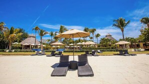 A beach resort with lounge chairs, umbrellas, and thatched-roof buildings. - Family Paradise Views, Jacuzzi and Beach Club (Cruz de Huanacaxtle)