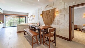 A spacious dining area with a stone wall, wooden furniture, and a view through a glass door. - Private Pool on Luxury PentHouse (Playa del Carmen)