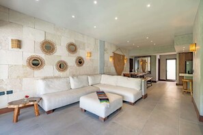 Ein großzügiger Wohnbereich mit einem weißen Sofa, einem kleinen Holztisch und einer Bank.