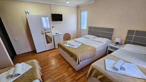 Habitación de hotel con dos camas, un escritorio, una silla, un televisor y una puerta.