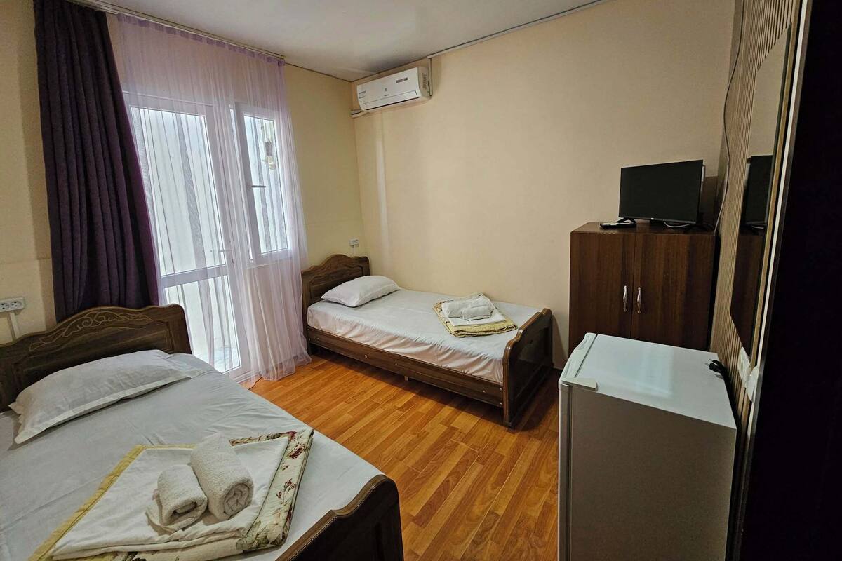 Una habitació d'hotel amb dos llits, un armari, una televisió i un aparell d'aire condicionat.