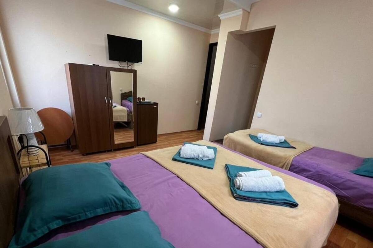 Una habitació d'hotel amb dos llits, una televisió, un armari i un mirall.