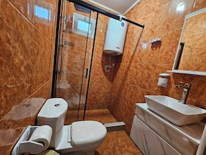 A bathroom with a glass-enclosed shower, a toilet, a sink, and a mirror. - hotel IMERI (Ureki)