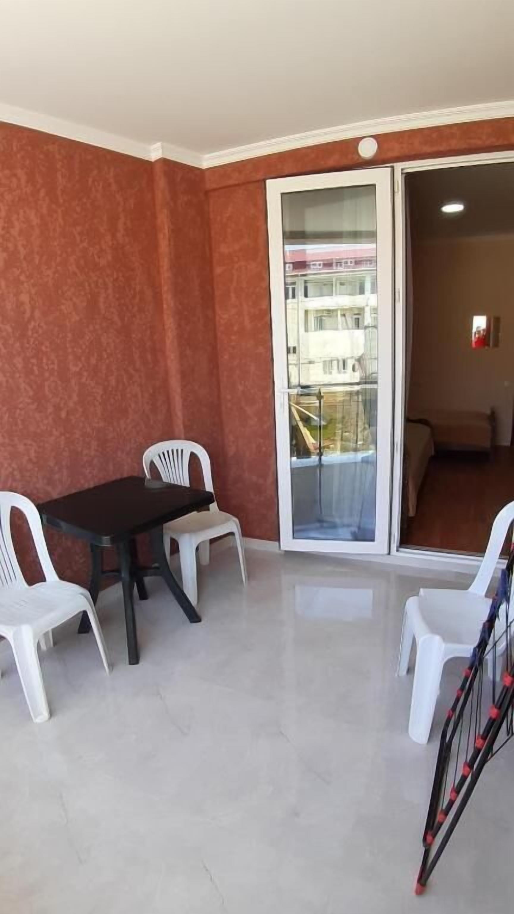 A room with a table and chairs, a sliding glass door, and a view of a building outside.