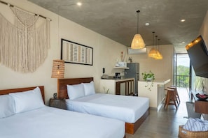 Ein Hotelzimmer mit zwei Betten, einer Küchenzeile, einem Essbereich und einem großen Fenster.