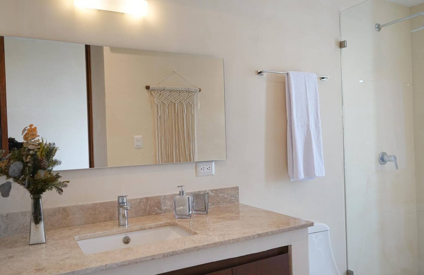 Un bagno con un lavabo in marmo, uno specchio, un porta asciugamani e una doccia.