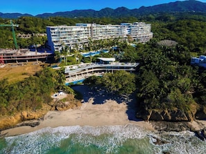 A multi-story hotel with a pool area, located near a beach with clear waters and a mountainous backdrop. - Amazing 3 Bedroom at Bolongo (Corral del Risco)