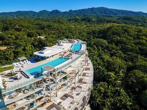 A resort with a large pool, multiple balconies, and a mountainous backdrop. - Amazing 3 Bedroom at Bolongo (Corral del Risco)