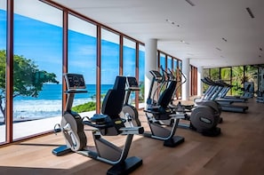 A gym with cardio machines and large windows overlooking a beach. - Amazing 3 Bedroom at Bolongo (Corral del Risco)