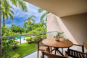 A balcony with a round wooden table and chairs, overlooking a swimming pool and lush greenery. - Amazing 3 Bedroom at Bolongo (Corral del Risco)