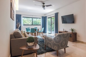 A modern living room with a sofa, armchair, dining table, and chairs. - Privileged Terrace with Hot Tub / Pool Ocean Views (Playa del Carmen)
