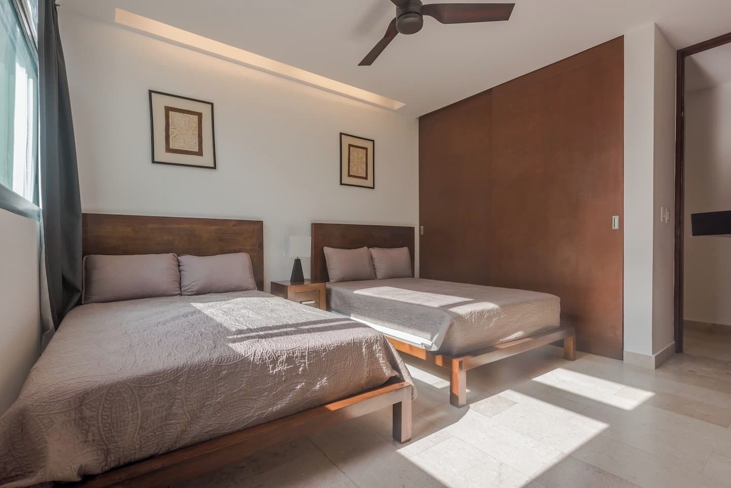 Une chambre d’hôtel moderne avec deux lits, un ventilateur de plafond et une grande armoire.