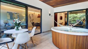 Een modern interieur met een houten plafond, een glazen eethoek en een badkuip in spa-stijl met twee glazen rode wijn.