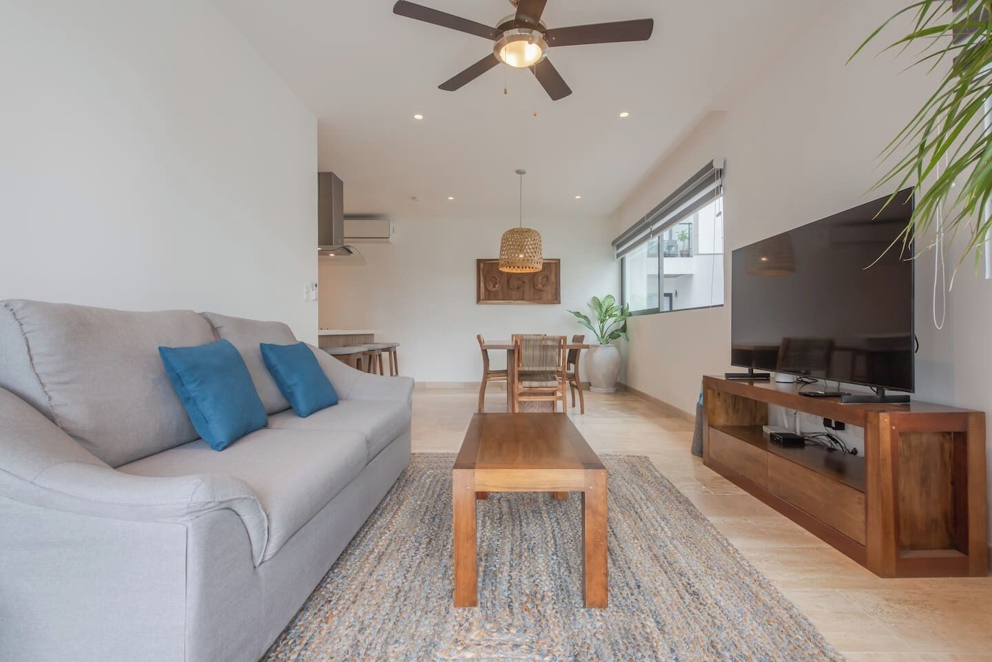 A living room with a sofa, coffee table, TV, and ceiling fan.