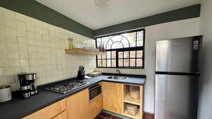 Et køkken med gasblus, kaffemaskine, rustfrit stål køleskab og et vindue med udsigt.