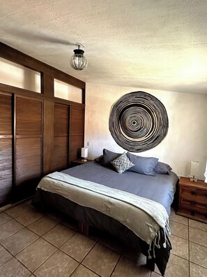 Une chambre à coucher comprenant un lit, une œuvre d’art murale, une table de chevet et une lampe.