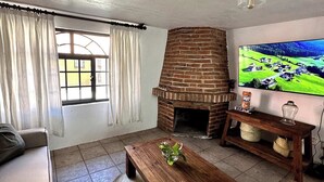 A living room with a brick fireplace, a television, a sofa, and a coffee table.