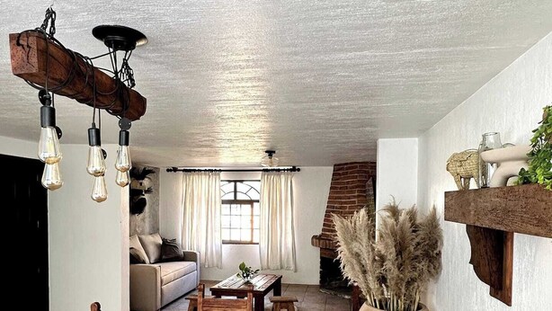 A spacious living area with a wooden dining table, a sofa, and a staircase leading to another level.
