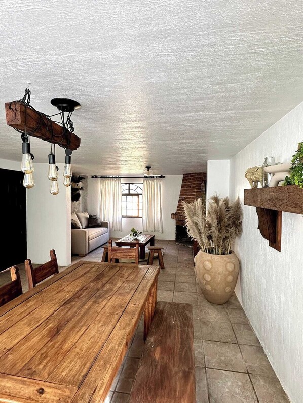 Un vaste espace de vie comprenant une table à manger en bois, un canapé et un escalier menant à un autre niveau.