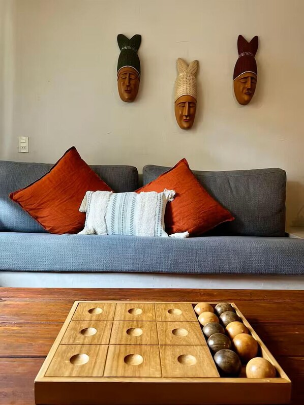 A living room with a grey sofa, red and white cushions, a wooden coffee table, and three wooden wall art pieces.