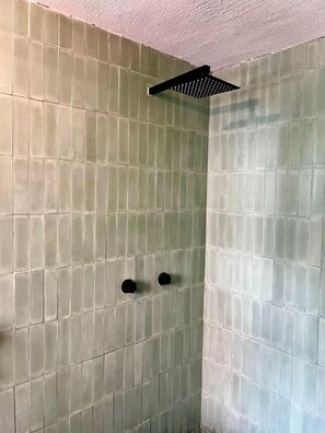 Une cabine de douche carrelée avec un pommeau de douche carré.