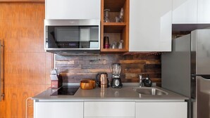 A modern kitchen with a microwave, blender, and coffee maker on the countertop, wooden cabinets, and a stainless steel refrigerator. - Ixchel Luxury PH Studio Priv Rooftop Pool 150 WiFi (Tulum)