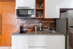 A modern kitchen with a microwave, blender, and coffee maker on the countertop, wooden cabinets, and a stainless steel refrigerator. - Ixchel Luxury PH Studio Priv Rooftop Pool 150 WiFi (Tulum)