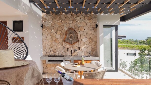 A rooftop terrace with a stone wall, a pool, and a table with chairs. - Ixchel Luxury PH Studio Priv Rooftop Pool 150 WiFi (Tulum)