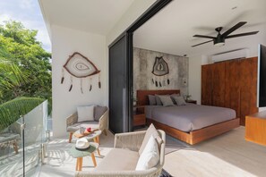 A modern bedroom with a large bed, a ceiling fan, and a view of greenery outside. - Ixchel Luxury PH Studio Priv Rooftop Pool 150 WiFi (Tulum)