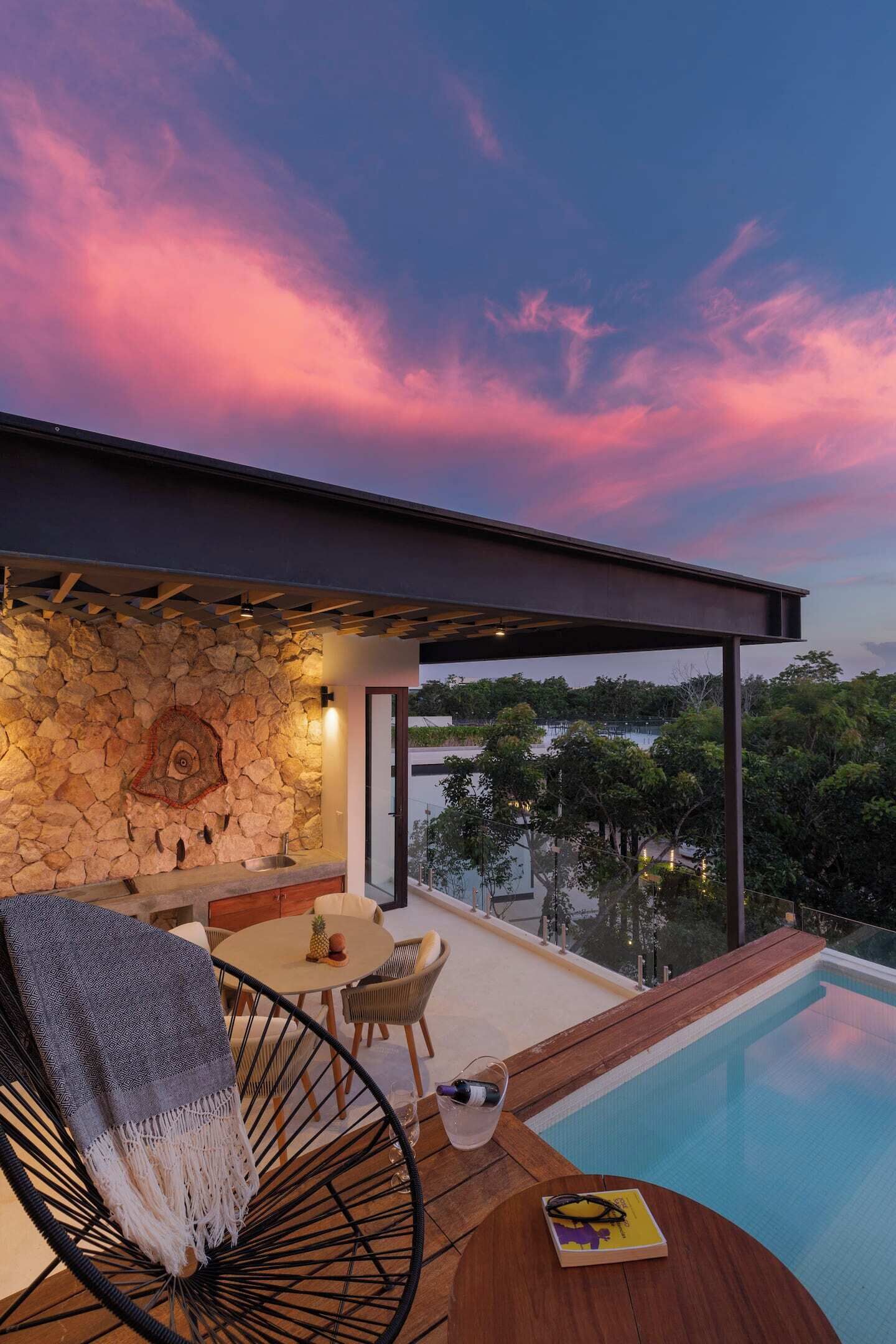 Zona relax esterna moderna con muro in pietra, piscina e vista sul paesaggio circostante.