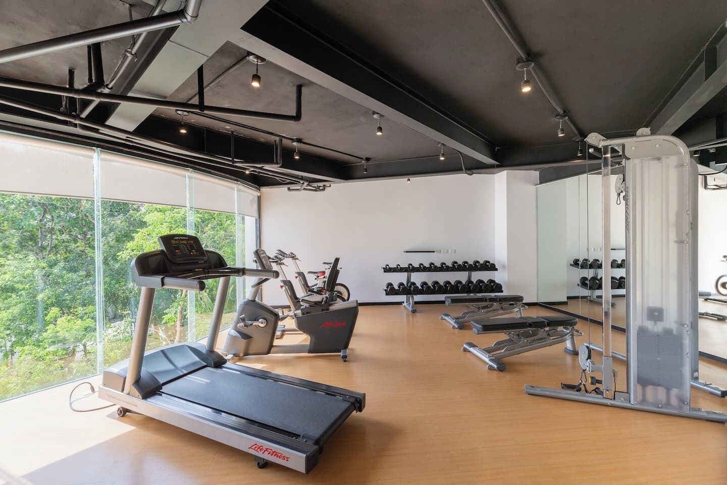 Une salle de sport équipée de machines de cardio, de bancs de musculation et d’haltères.