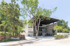 A modern building with a covered entrance, surrounded by trees and greenery. - Ixchel Luxury PH Studio Priv Rooftop Pool 150 WiFi (Tulum)