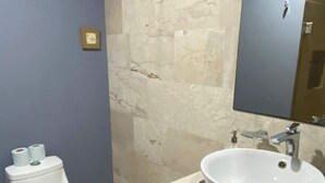 Ein Badezimmer mit Toilette, Waschbecken, Spiegel und Marmorwänden.