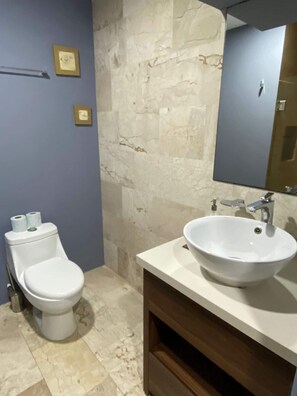 Ein Badezimmer mit Toilette, Waschbecken, Spiegel und Marmorwänden.