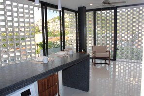 A modern kitchen with a marble countertop, a wooden cabinet, and a chair. - Studio in Romantic Zone at Rincon de Almas (Puerto Vallarta)