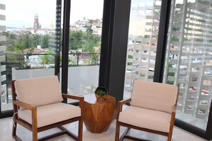A balcony with two wooden chairs and a small wooden table with a green plant. - Studio in Romantic Zone at Rincon de Almas (Puerto Vallarta)
