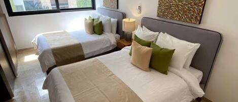 Habitación de hotel con dos camas, un ventanal grande y obras de arte en las paredes.