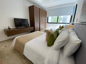 Ein modernes Hotelzimmer mit Bett, Fernseher, Kleiderschrank und Fenster mit Aussicht.