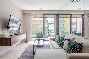 Ein modernes Wohnzimmer mit einer Couch, Fernseher und einem Balkon mit Blick auf Gebäude.