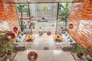 Ein modernes Interieur mit einer zentralen Sitzecke, hängenden, kugelförmigen Lampen und Blick durch ein großes Fenster.