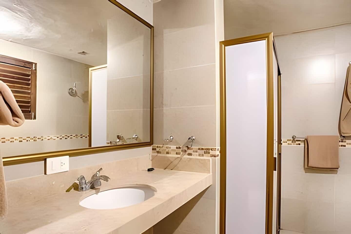 A bathroom with a sink, mirror, and shower.