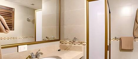 A bathroom with a sink, mirror, and shower.