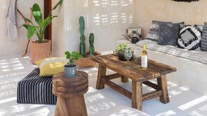 Habitació amb sostre de vimet, cadira espanyola, taula de cafè de fusta i sofà amb coixins estampats.