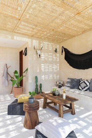A room with a woven ceiling, a hammock, a wooden coffee table, and a sofa with patterned cushions. - Boho Style Penthouse with Private Pool 150 Wifi (La Veleta)